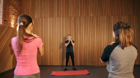 Fitness instructor leading a training session with two women in a modern gym setting.